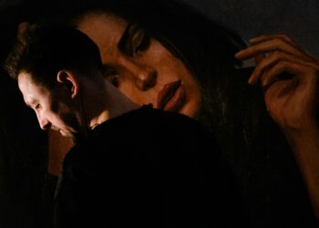 A man gazes thoughtfully at a painting depicting a woman, immersed in the artwork's details and emotions