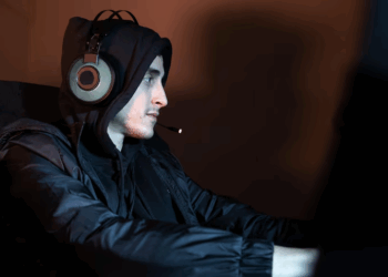 A man in a hoodie wearing headphones, focused and immersed in listening to music or audio